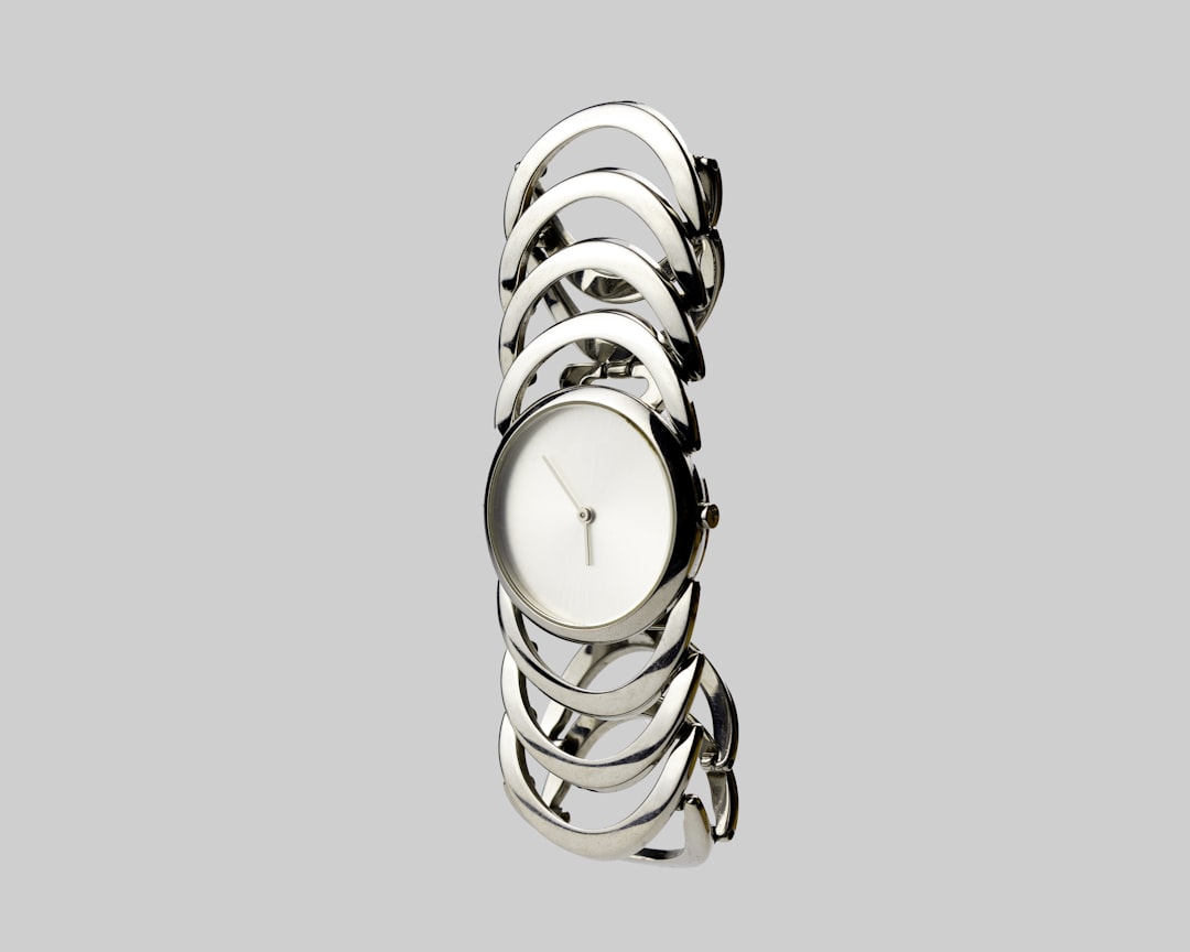 a-white-clock-sitting-on-top-of-a-metal-bracelet-sr3ql4efmtu